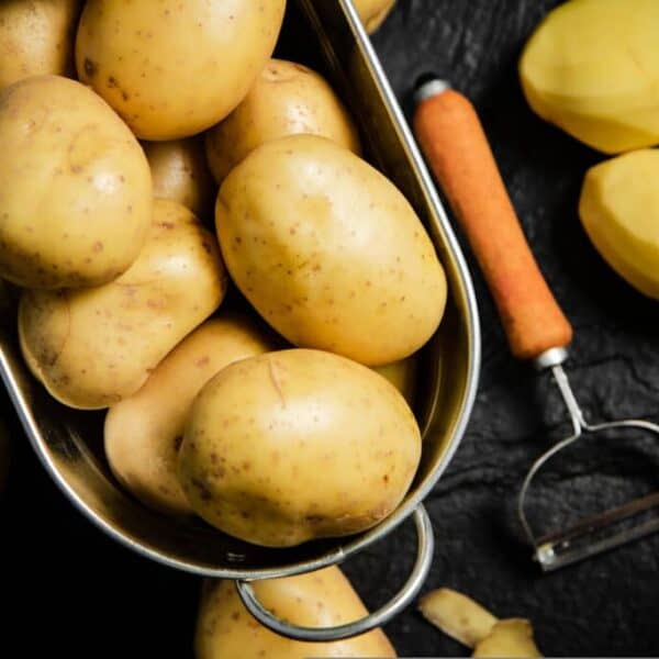 Yellow potatoes in basket with a potato peeler