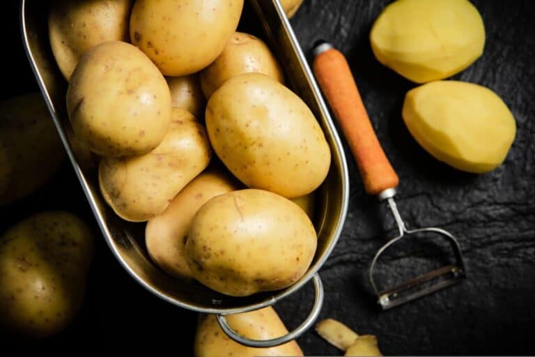 Yellow potatoes in basket with a potato peeler