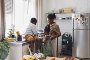 Happy mother, daughter and son preparing vegetables for lunch over a kitchen sink.
