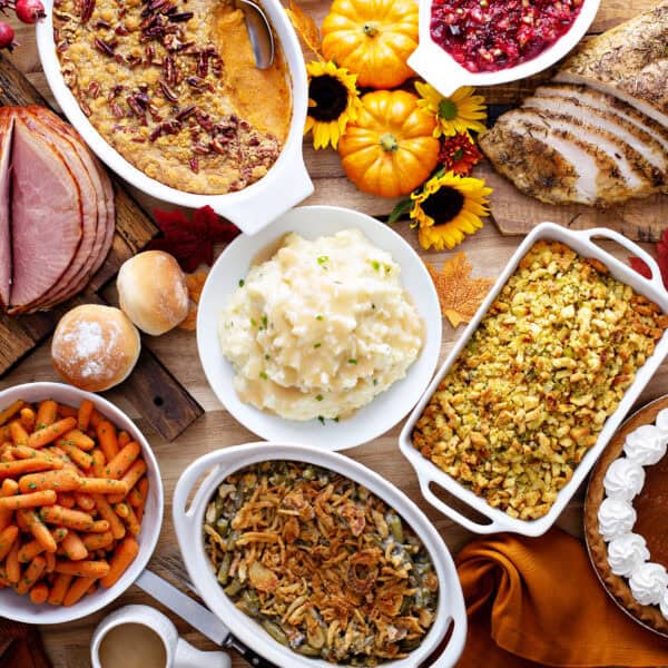 Thanksgiving table with roasted turkey, sliced ham and side dishes